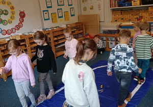 Dzieci idą po elipsie z dzwonkiem w ręku podczas ćwiczenia ciszy