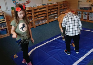 Dzieci idą po elipsie z dzwonkiem w ręku podczas ćwiczenia ciszy