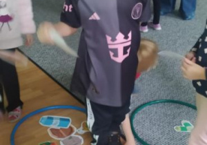 Chłopiec segreguje odpady układając zdjęcie w obręczy w odpowiednim kolorze