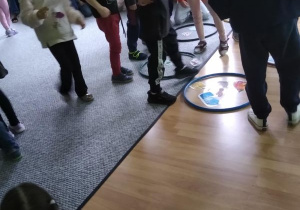 Dzieci segregują odpady układając zdjęcie w obręczy w odpowiednim kolorze