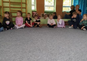 Dzieci siedzą w kręgu i słuchają prowadzącej zajęcia