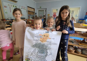 Dzieci prezentują wykonany przez siebie w grupie plakat, na którym znajduje się Dora