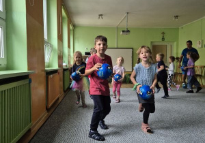 Dzieci biegają z piłkami