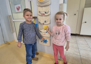 Chłopiec i dziewczynka wkładają swoją wizytówkę do kieszonki z uśmiechniętą buźką