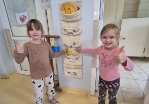 Dwie dziewczynki wkładają swoją wizytówkę do kieszonki z uśmiechniętą buźką