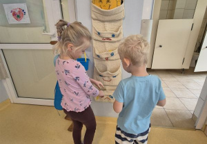 Chłopiec i dziewczynka wkładają swoją wizytówkę do kieszonki ze smutną buźką