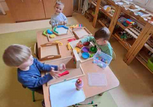 Dzieci młodsze przy stoliku w czasie wykonywania indywidualnych ćwiczeń z wykorzystaniem montessoriańskiego materiału rozwojowego