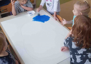 Dziewczynka stempluje farbami tło do pracy plastycznej