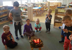 Dzieci modlą się wokół wieńca adwentowego z zapalonymi świecami