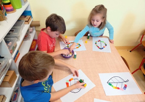 Dzieci wyklejają kształt liścia kolorowymi kwadratami