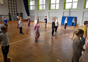 Dzieci stoją w wyznaczonych miejscach i słuchają instruktażu ćwiczeń