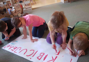 Dzieci przygotowują plakat z napisem Kibicujemy Polsce