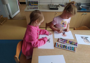 Dziewczynki siedzą przy stole i rysują Janusza Korczaka