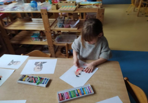 Dziewczynka siedzi przy stole i rysuje Janusza Korczaka