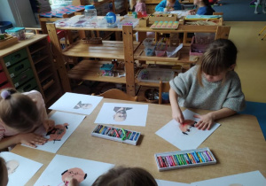 Dziewczynki siedzą przy stole i rysują Janusza Korczaka