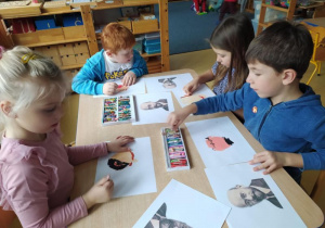 Dzieci siedzą przy stole i rysują Janusza Korczaka