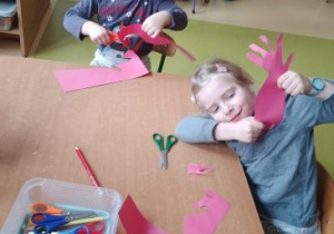 Dziewczynki wycinają odrysowane swoje ręce