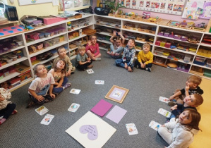 Dzieci siedzą na dywanie w czasie zajęć dotyczących praw najmłodszych