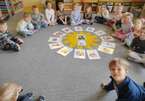 Dzieci siedzą w kręgu i poznają ,,montessoriańskie słonecznko praw dziecka".