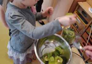 Zosia wkłada kiwi do blendera