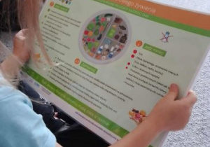Dziewczynka ogląda planszę dotyczacą zdrowego żywienia