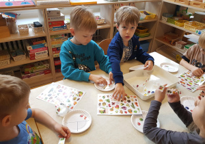 Dzieci przyklejają na talerzyki naklejki przedstawiające owoce, warzywa, węglowodany i nabiał
