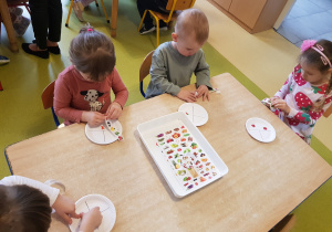Dzieci przyklejają na talerzyki naklejki przedstawiające owoce, warzywa, węglowodany i nabiał