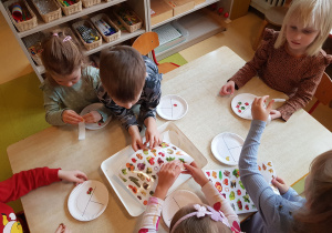Dzieci przyklejają na talerzyki naklejki przedstawiające owoce, warzywa, węglowodany i nabiał