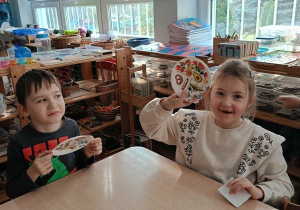 Dziewczynka i chłopiec prezentują talerz z naklejkami zdrowych produktów