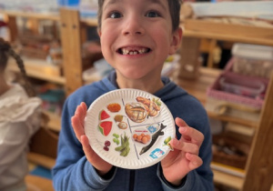 Chłopiec prezentuje talerz z naklejkami zdrowych produktów