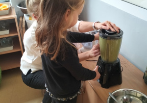 Pola z pomocą osoby dorosłej włącza sokowirówkę