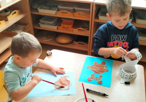 chłopcy malują swoje misie farbami