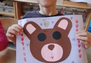 Natan prezentuje swoją pracę plastyczną przedstawiającą misia