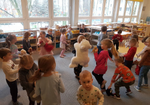 Dzieci tańczą z misiami na dywanie