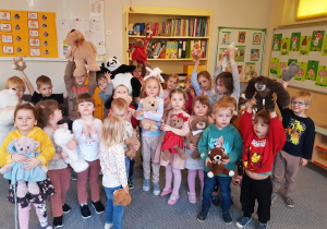 Dzieci pozują do wspólnego zdjęcia, prezentując swoje misie