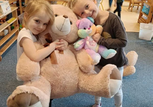 Dwie dziewczynki stoją i przytulają się do swoich misiów