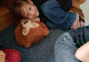 Dziewczynka leży wtulona w pluszowego misia