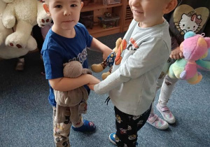 Dwóch chłopców tańczy ze swoimi pluszakami trzymając się za ręce