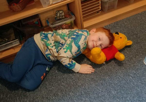 Chłopiec leży wtulony w pluszowego Kubusia Puchatka