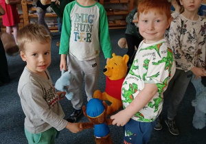 Trzech chłopców tańczy ze swoimi pluszakami trzymając się za ręce