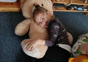 Dziewczynka leży na dużym pluszowym misiu