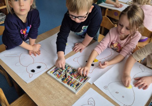 Dzieci siedzą przy stoliku i rysują misie