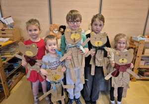 Dzieci pozują do zdjęcia z wykonanymi przez siebie misiami z kartonów, w tle pluszowe misie