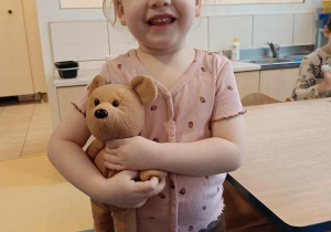 Dziewczynka pozuje do zdjęcia z pluszowym misiem