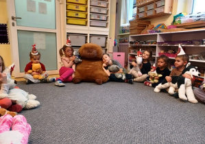 Dzieci na dywanie siedzą ze swoimi misiami