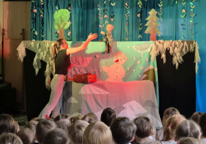 Scena oraz występujący na niej: pacynka - chłopiec i aktorka, na widowni siedzą dzieci