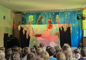 Scena oraz występujące na niej pacynki - czarownica i wilk, na widowni siedzą dzieci