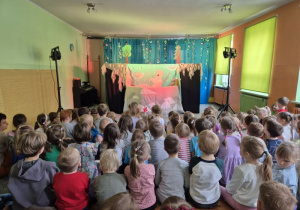 Dzieci siedzą na widowni i oglądają przedstawienie