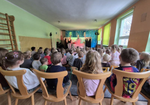 Dzieci siedzą na widowni i oglądają teatrzyk