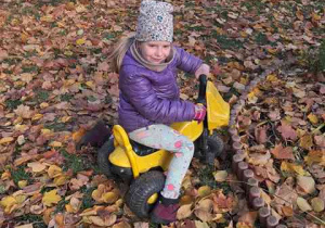 Zosia podczas zabaw w ogrodzie jedzie na motorku